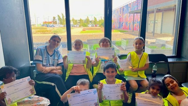Children and a staff member celebrating with participation certificates