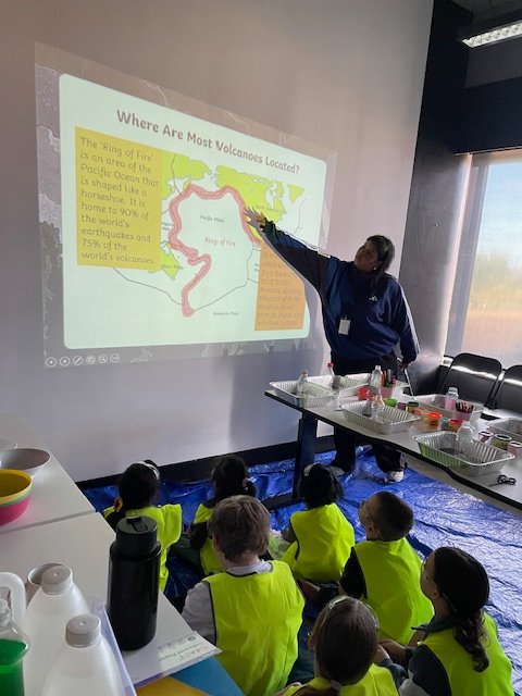 An educator explains volcanoes to children during a group learning activity