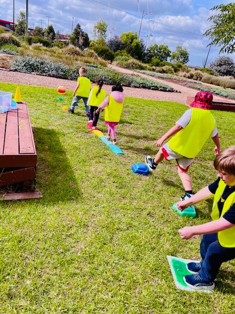 Children taking turns on colourful stepping stones in the garden