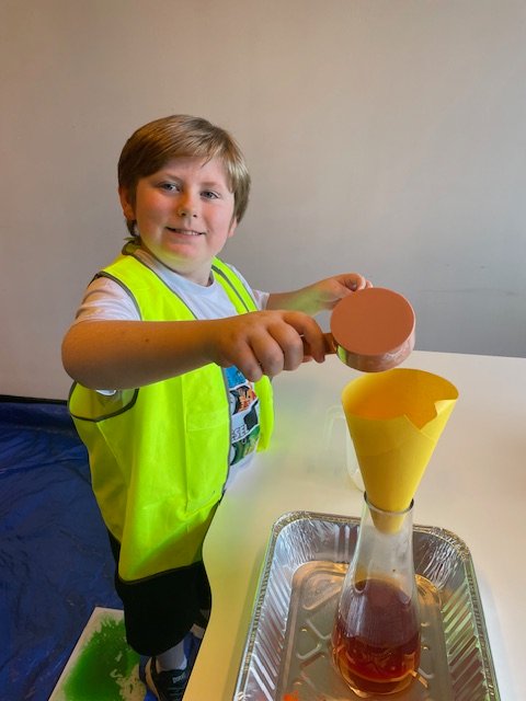 A child pours ingredients through a funnel during a science activity